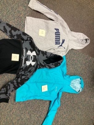 Lost and found items, three hoodies (solid blue, gray w/Puma logo, black camo w/Under Armor logo).